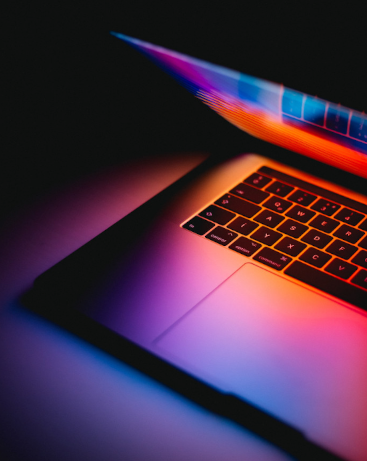 Half-closed laptop with blue, pink and orange light