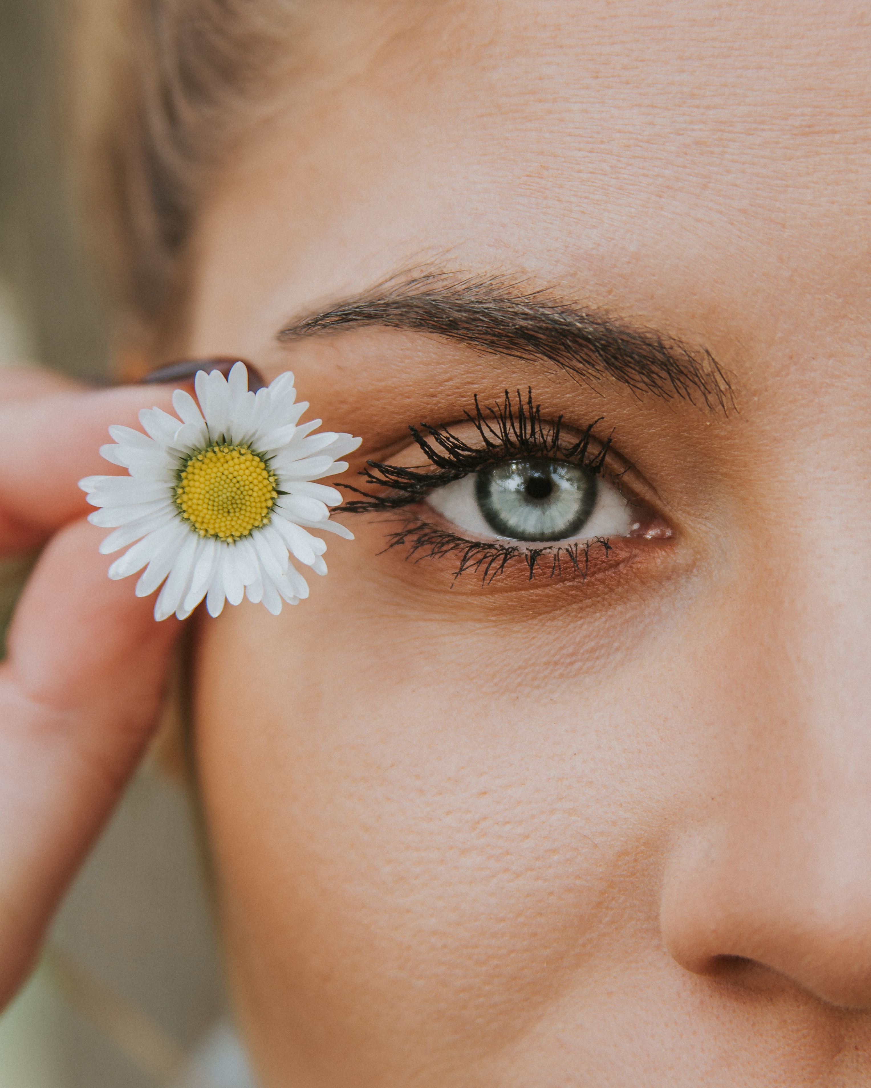 Femme tenant une marguerite tout près de son oeil bleu