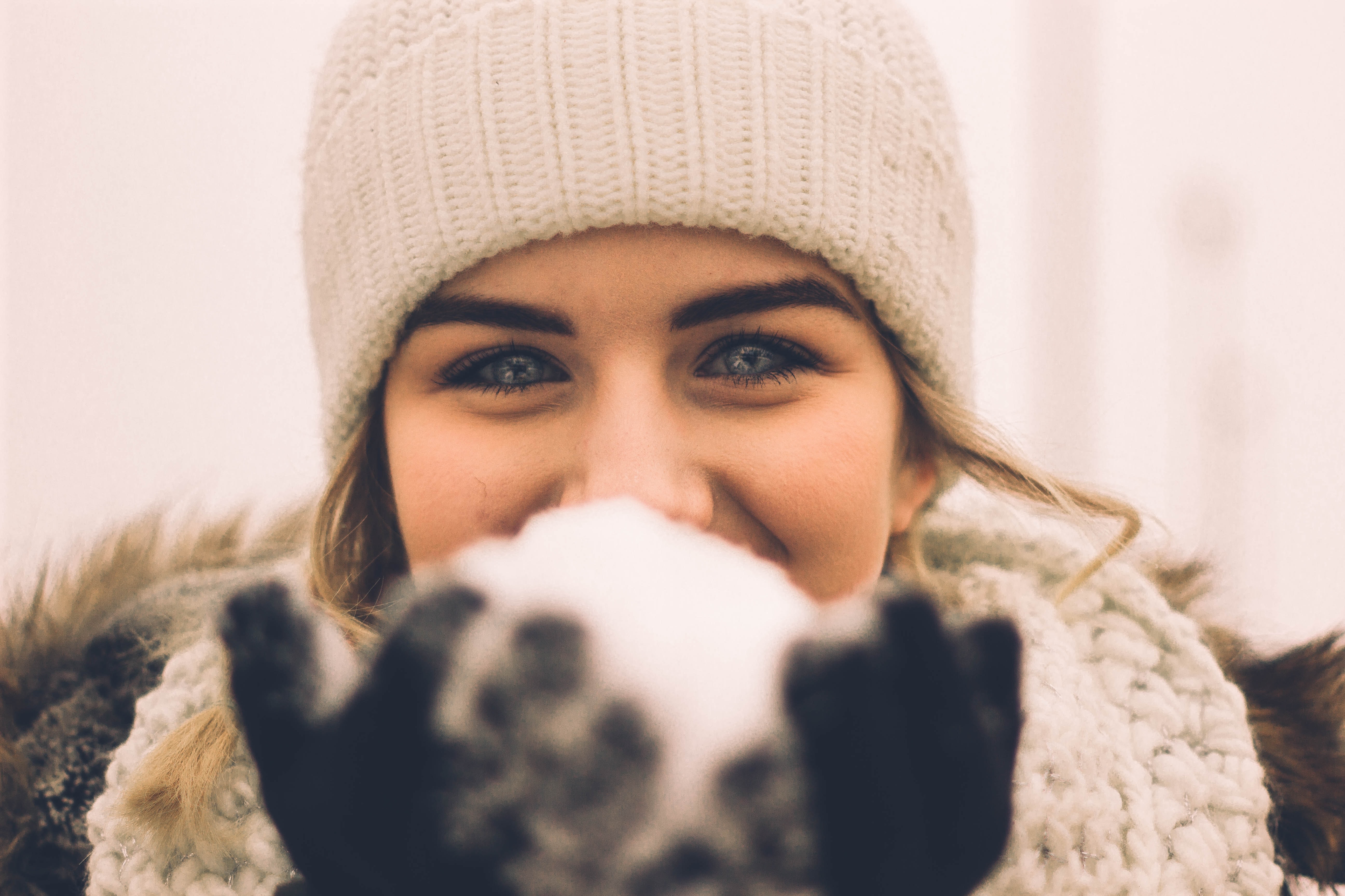 Femme aux yeux bleus tenant une balle de neige devant son visage