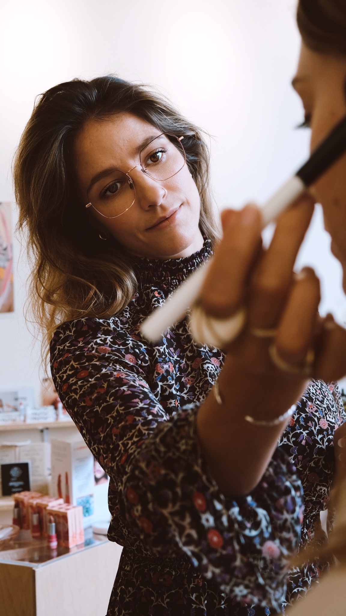 Léa Bégin avec une robe à fleurs maquillant quelqu'un