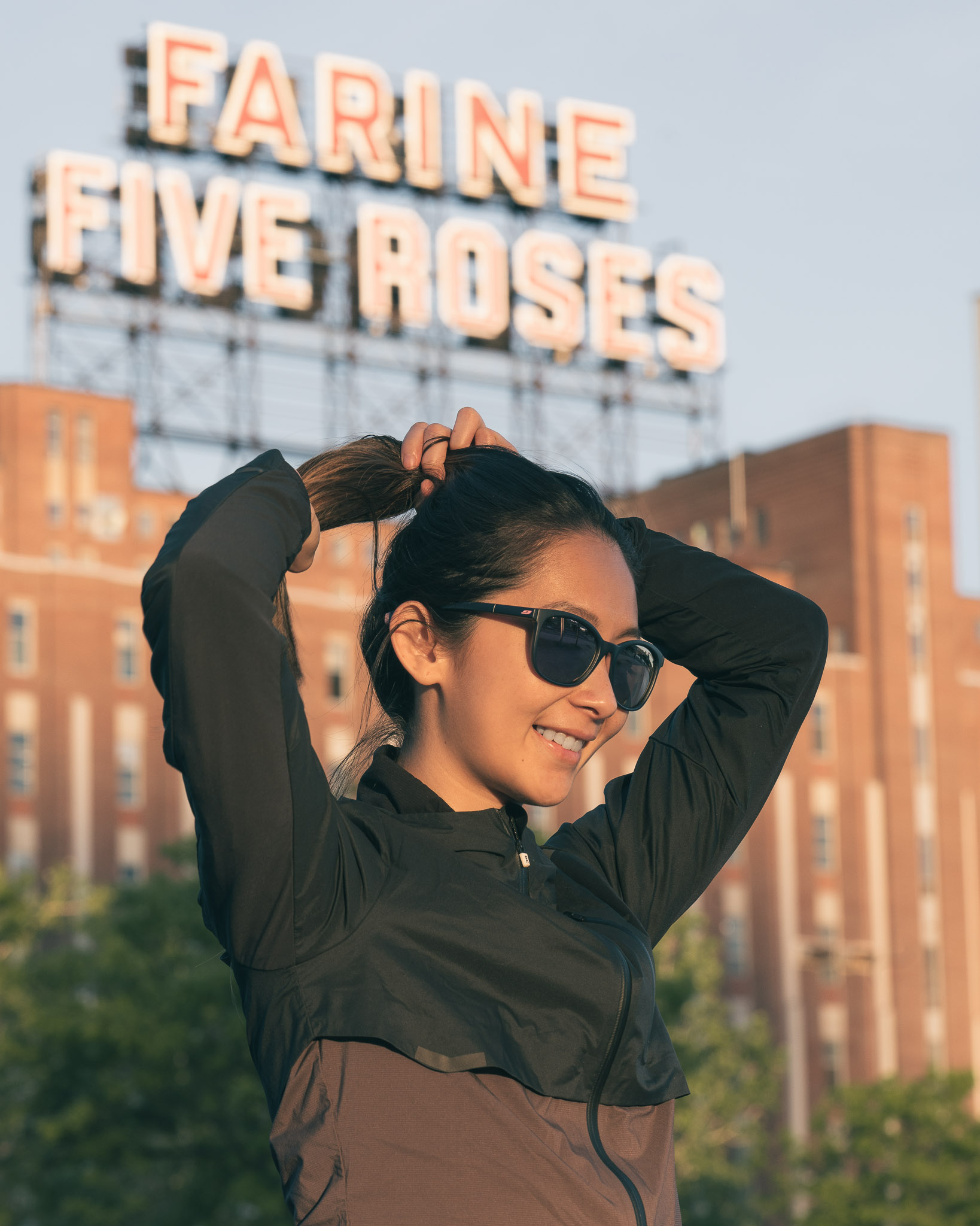 Woman in sportswear replacing her hair in front of the Farine Five Roses factory