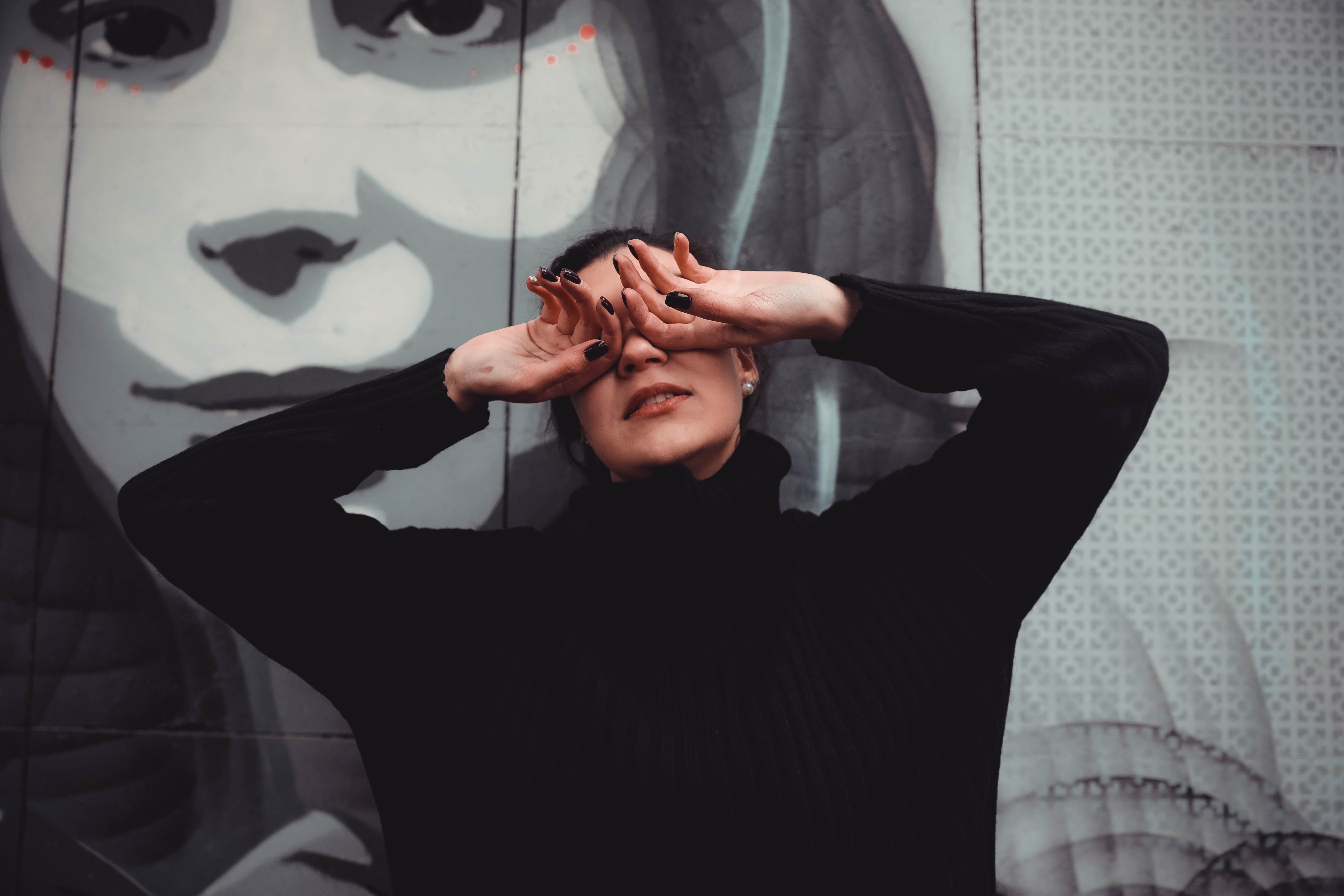 woman dressed in black hiding her eyes with the back of her hands